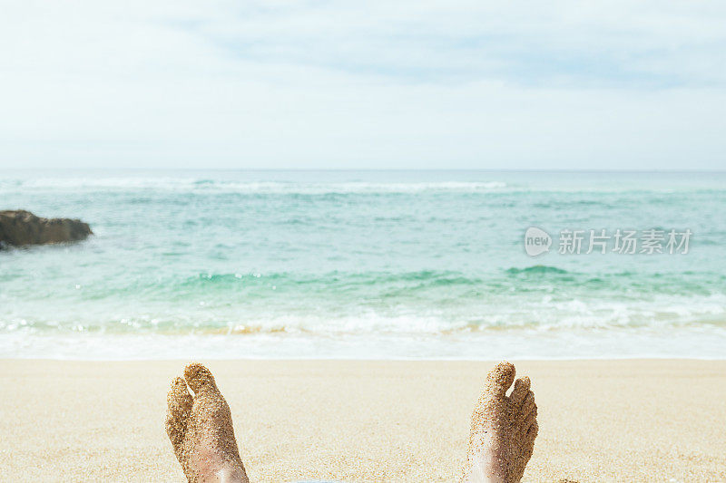 Pedn Vounder Cornwall海滩上，男人被沙子覆盖的脚